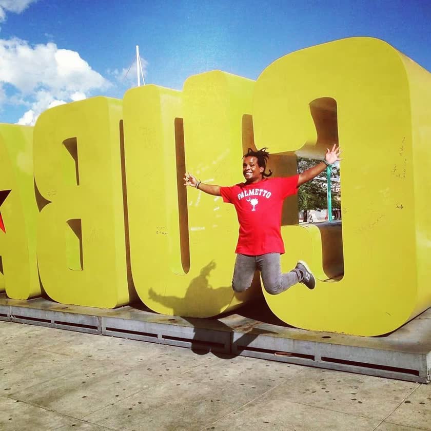 Yoyo jumping with open arms in front of the giant yellow CUBA letters, February 2019